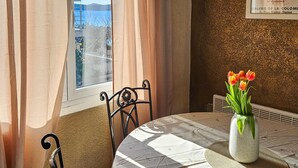 Een eethoek met een tafel, stoelen, een vaas met bloemen en een raam met gordijnen.