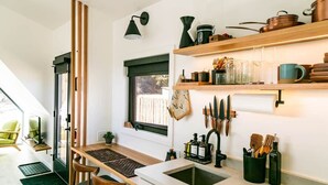 A modern kitchen with a wooden countertop, a sink, and a window with blinds.
