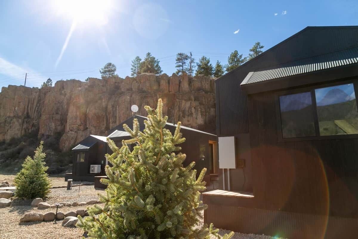 Ein modernes Gebäude mit geneigtem Dach, einer Satellitenschüssel und einem kleinen Baum im Vordergrund.