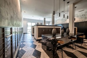 A modern kitchen with a marble island, pendant lighting, and a herringbone floor pattern. - Landing | Incredible 2BD, Clubhouse, Gym (Lewisville)
