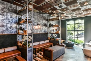 A modern interior with a high ceiling, metal beams, and a large window offering a view of the outdoors. - Landing | Stunning 2BD, Courtyard, Gym (Lewisville)