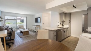 A modern apartment with a dining area, kitchen, and a balcony with a view. - Landing | Spectacular 1BD, Courtyard (Paradise)