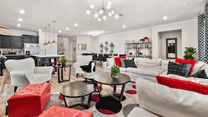 Ein modernes Wohnzimmer mit einer Couch, Sesseln, einem Couchtisch und einem Essbereich mit Stühlen und Tisch.
