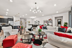 Ein modernes Wohnzimmer mit einer Couch, Sesseln, einem Couchtisch und einem Essbereich mit Stühlen und Tisch.
