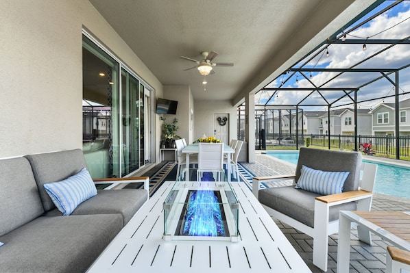 A covered outdoor area with a pool, seating, and a ceiling fan. - Mickey, Pooh & Jurassic Rooms • Theater • Arcade & Pinball • Pool & Spa • Resort (Davenport)