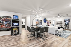 Ein modernes Wohnzimmer mit Essbereich, Deckenventilator und verschiedenen Filmplakaten an den Wänden.