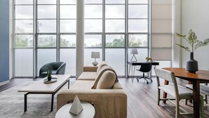 A modern office space with a large window, a sofa, a desk, and a chair. - Landing | Stylish 1BD, Courtyard (Kansas City)