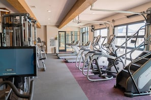 Ein Fitnessstudio mit Laufbändern, Crosstrainern und Kraftgeräten.