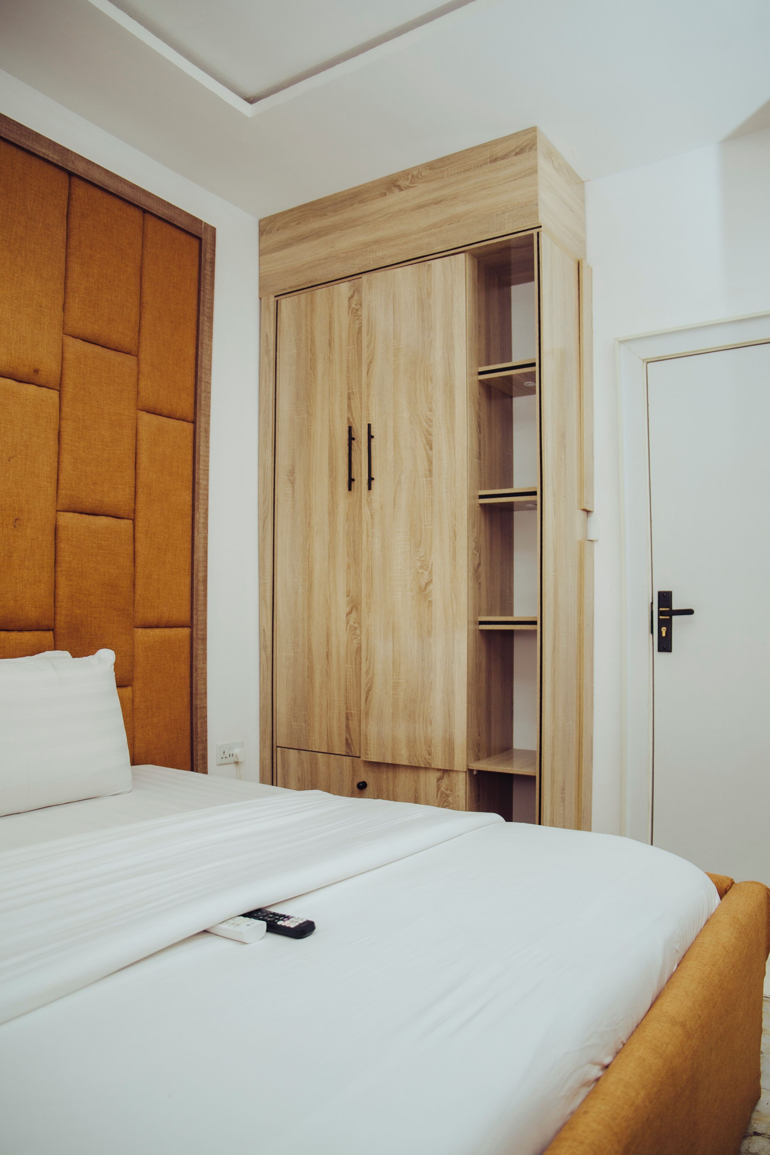 A bedroom with a bed, a wooden wardrobe, and a door.