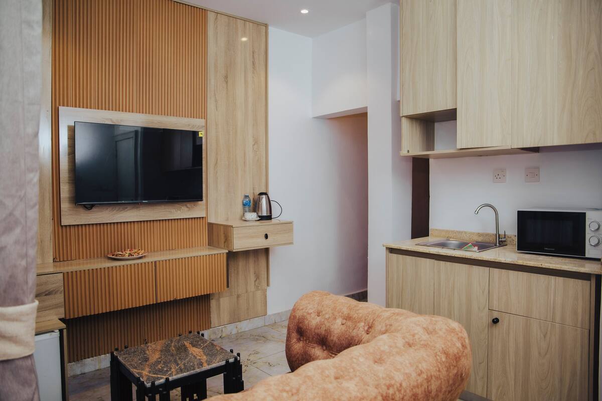 Eine moderne Küche mit Holzschränken, einer eingebauten Mikrowelle und einem Essbereich mit Tisch und Bank.