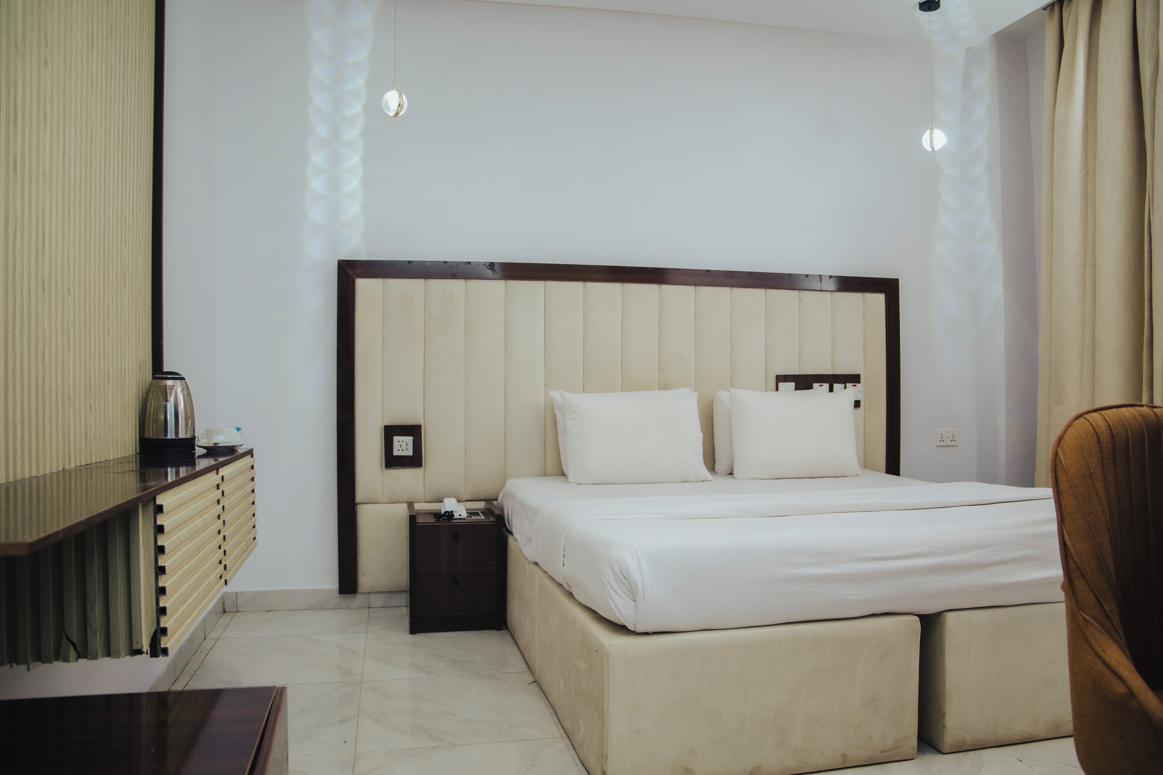 A hotel room with a bed, bedside table, and a chair.