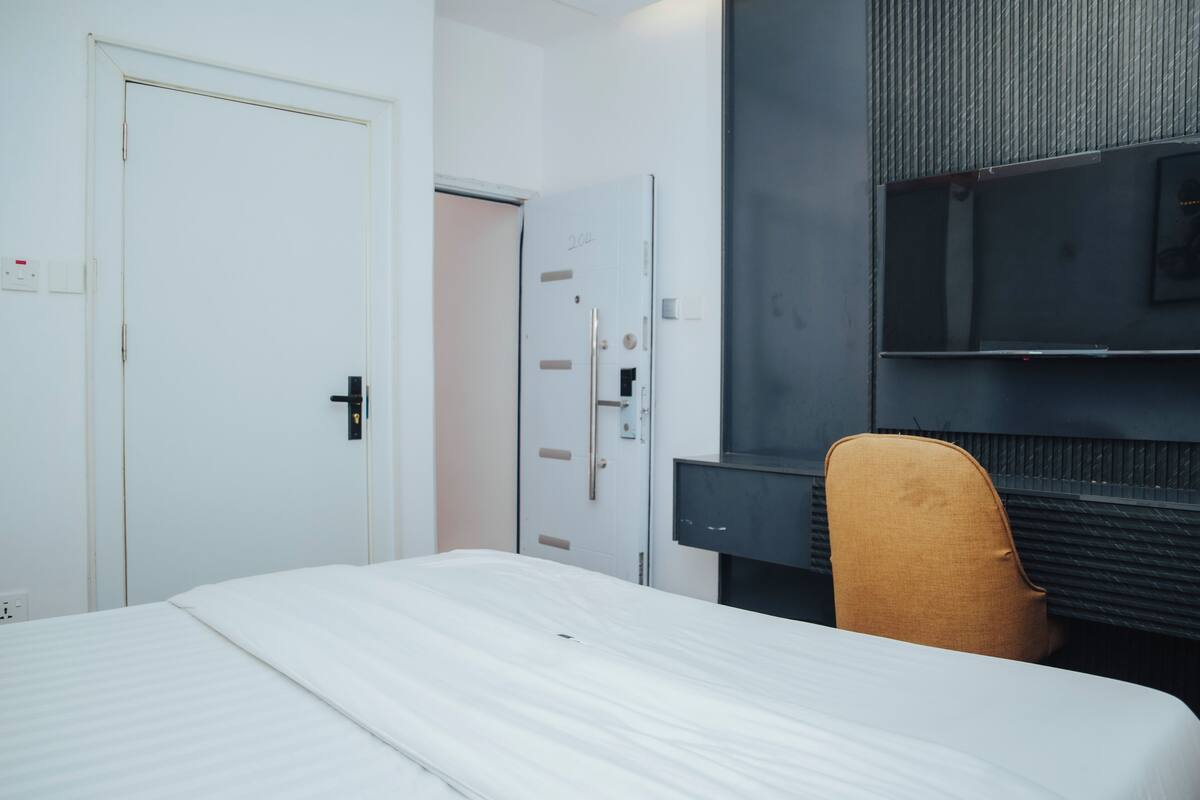 Ein Hotelzimmer mit Bett, Tür, Kleiderschrank, Fernseher und Stuhl.