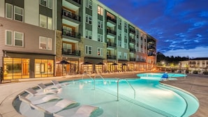 Ein mehrstöckiges Hotel mit Pool, Außenbereich und einer gut beleuchteten Fassade.