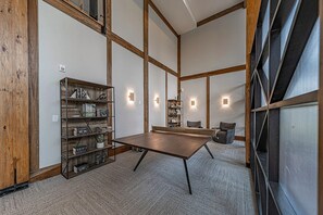 Une salle de conférence avec une longue table, deux étagères et une chaise.