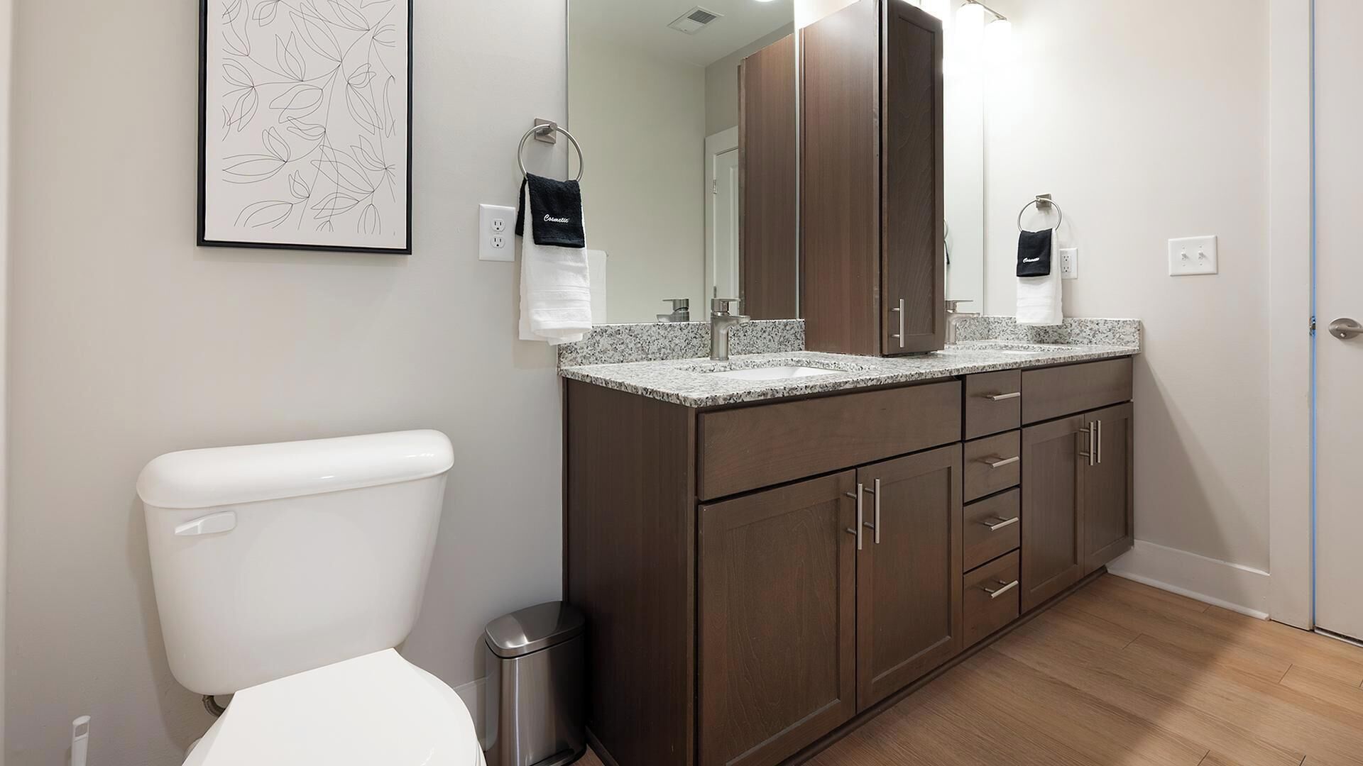 Un baño moderno con inodoro, lavabo y muebles de madera oscura.