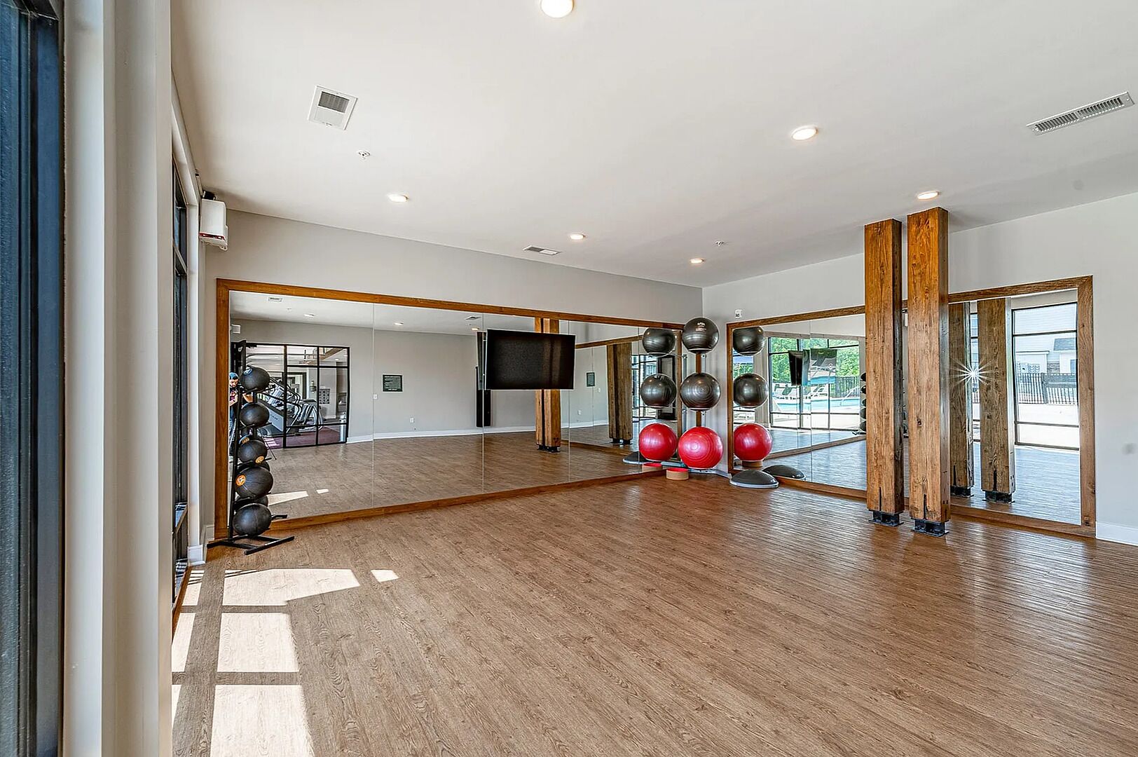 Una habitación amplia con piso de madera, ventanas grandes y equipo de ejercicio.