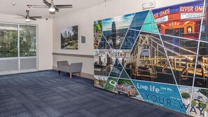 Ett modernt kontorsutrymme med takfläktar, ett stort fönster, en grå soffa och en vägg med en collagebestående av bilder av stadslandskap samt texterna ”Sofistikerat” och ”Lev livet på ditt sätt”.