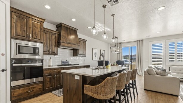 A modern kitchen with wooden cabinets, stainless steel appliances, and a central island with bar stools. - Private Balcony Hot Tub | Pool | Near Golf Course (Washington)