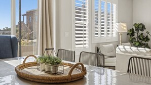 A modern living room with a glass table, wicker side table, and a view of the outside. - Private Balcony Hot Tub | Pool | Near Golf Course (Washington)