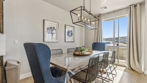 A dining area with a glass table, metal chairs, a hanging light fixture, and framed artwork on the wall. - Private Balcony Hot Tub | Pool | Near Golf Course (Washington)
