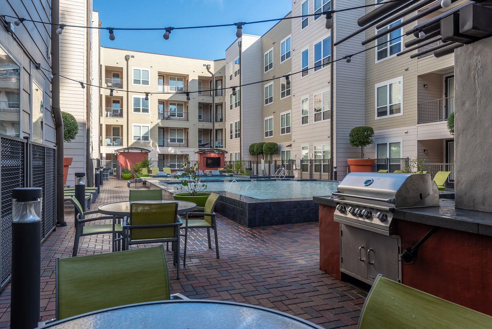 An outdoor patio with a pool, grilling area, and seating.