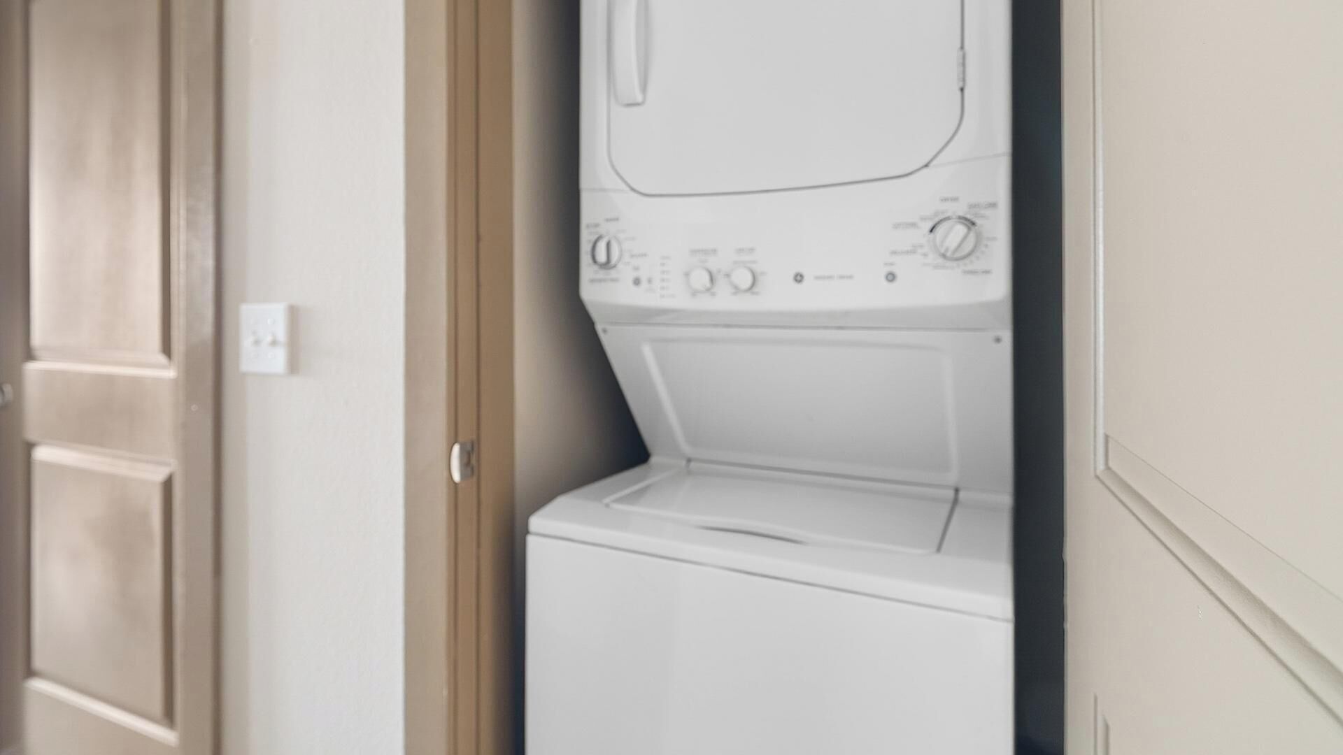 Een wasserette met een wasmachine en droger, een deur en een lichtschakelaar.