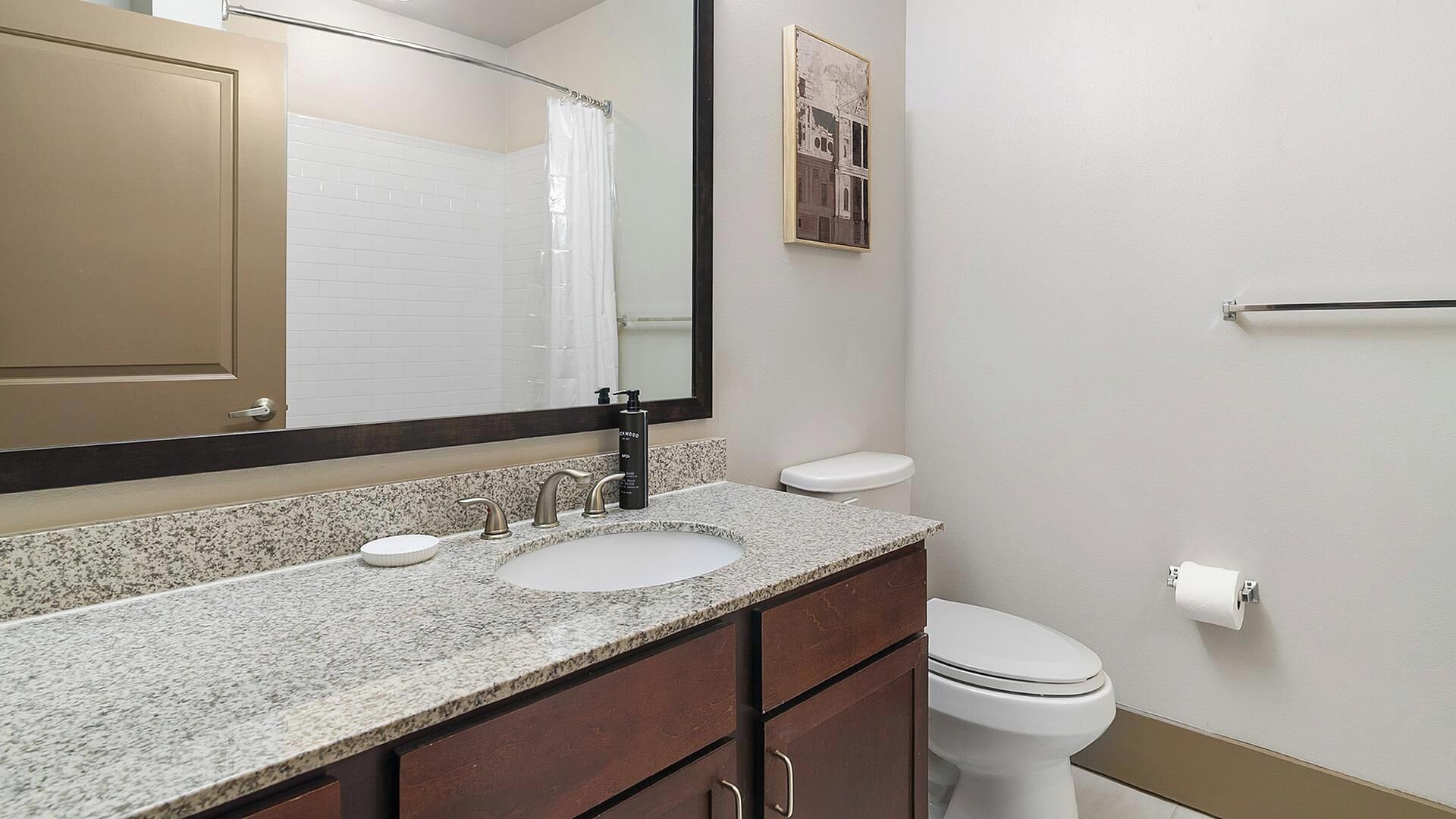 Un bagno con lavandino, specchio, WC e portasciugamani.