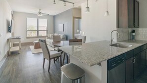 Een moderne keuken met een granieten aanrecht, een vaatwasser en een plafondventilator.