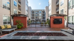 Een binnentuin met terras, vuurkorf en een televisiescherm.