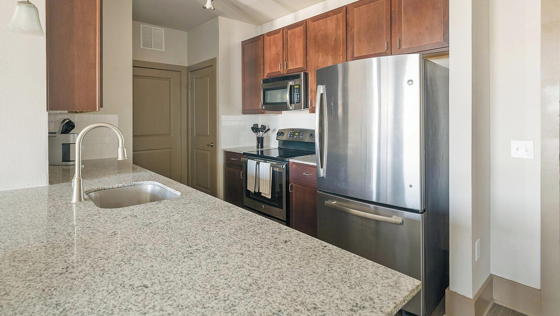 A kitchen with granite countertops, stainless steel appliances, and wooden cabinets.