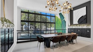 A modern dining area with a large table, chairs, and a view through large windows. - Landing | Spectacular 2BD, Pool (Miami)