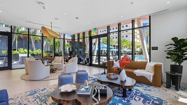 A modern hotel lobby with large windows, comfortable seating, and a pool view. - Landing | Spectacular 2BD, Pool (Miami)