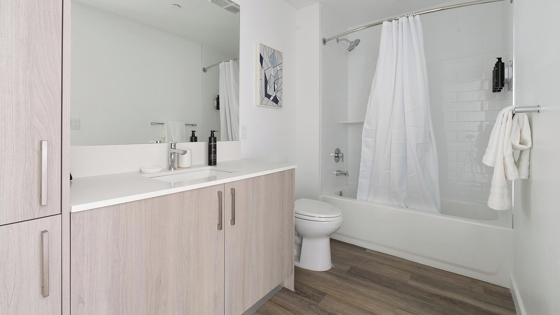 A modern bathroom with a shower, toilet, sink, and cabinet.