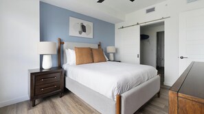 A bedroom with a bed, nightstands, a wardrobe, and a door to a bathroom. - Landing | Chic 2BD, Pool (Miami)