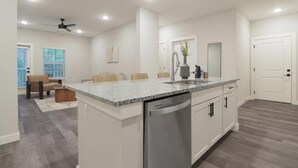 Eine moderne Küche mit einer Granit Arbeitsplatte, Edelstahlgeräten und einem eingebauten Geschirrspüler.