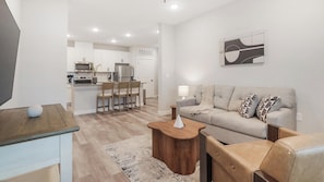 Ein modernes Wohnzimmer mit Sofa, Couchtisch und Fernseher auf einem Holzboden.