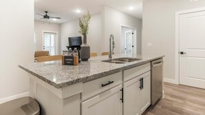 Eine moderne Küche mit Granit-Arbeitsplatten, Edelstahlgeräten und einem integriertem Geschirrspüler.