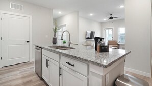 Cozinha moderna com bancadas de granito, armários brancos e lava-louças embutida.