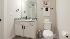 Une salle de bain avec des toilettes, un lavabo et des placards.