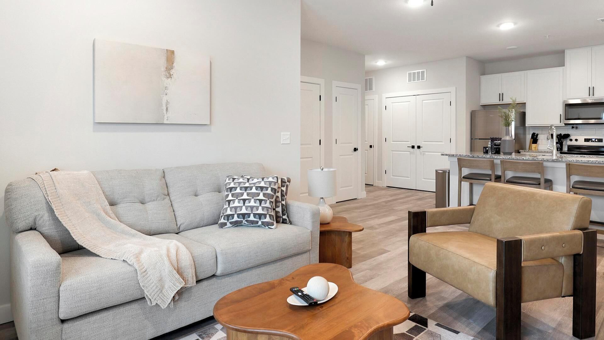A modern living room with a sofa, armchair, coffee table, and a remote control on the table.