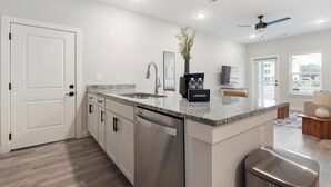 Eine moderne Küche mit Edelstahlgeräten, einer Granit Arbeitsplatte und einem Essbereich mit Fernseher.