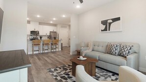 A modern living room with a grey sofa, a coffee table, and a patterned rug. - Landing | Modern 2BD in Shell Point (Port Royal)