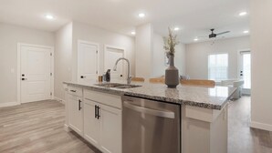A modern kitchen with granite countertops, stainless steel appliances, and a central island. - Landing | Modern 2BD in Shell Point (Port Royal)
