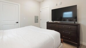 A bedroom with a bed, a dresser, a television, and two doors. - Landing | Beautiful 1BD in Shell Point (Port Royal)