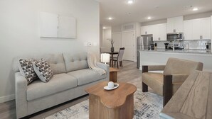 Un salon moderne comprenant un canapé, une table basse et un coin repas avec des chaises.