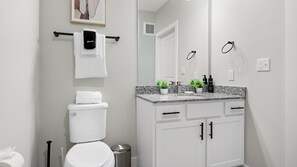 Ein modernes Badezimmer mit Toilette, Waschbecken und Schränken.