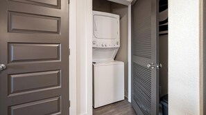 A laundry room with a washer and dryer, a door with a handle, and a vented wall. - Landing | Amazing 1BD in Medical Center (San Antonio)