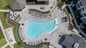Vue aérienne d’un espace piscine avec des chaises longues et un coin salon abrité.