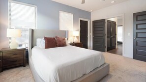 Quarto com cama, mesas de cabeceira, cômoda e porta para um armário.
