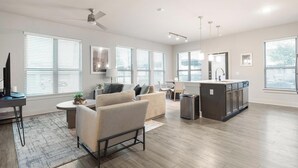 A spacious living area with a sofa, a dining table, and a kitchen island. - Landing | Chic 2BD in Medical Center (San Antonio)